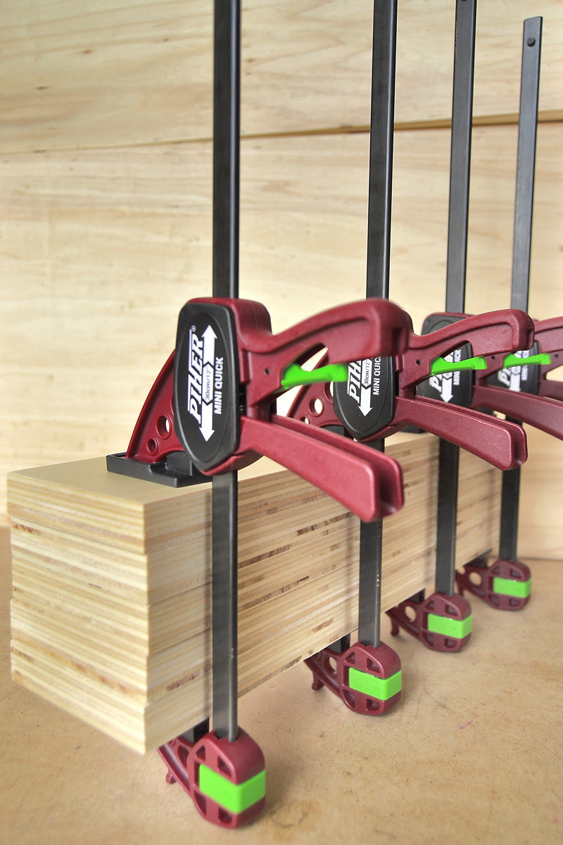 A woodworker using the 30cm Piher Mini Quick Clamp for a small assembly project.