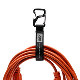 An extension cord neatly coiled and secured by the Diamondback Carabiner Cord Loop, ready for transport.