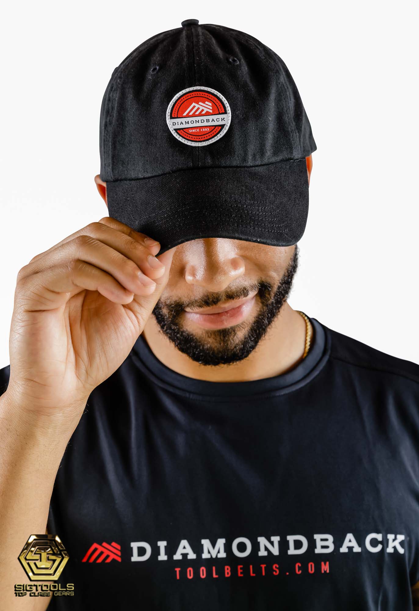 A person wearing a Diamondback red dad hat with the brand's logo on the front, smile as he's showcasing the hat's style and fit when worn