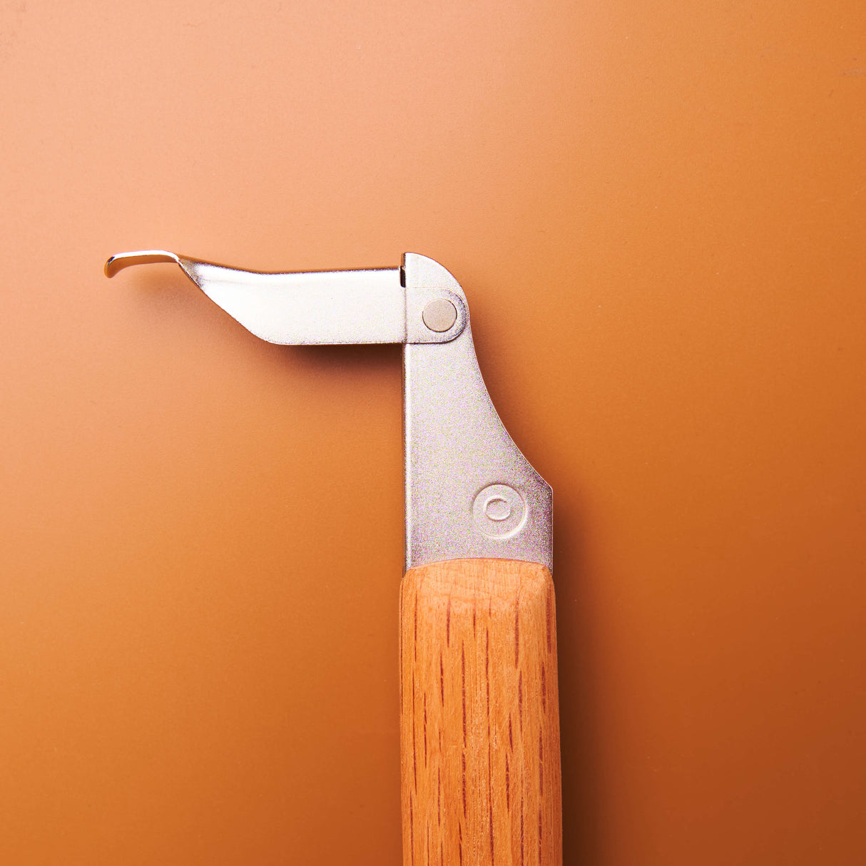 A close-up of the premium 215mm Red Oak handle of the KAKURI saw, showing the unique, snag-free blade latch.