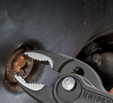 The powerful serrated front jaws of the KNIPEX TwinGrip removing a stripped bolt from a flat surface.
